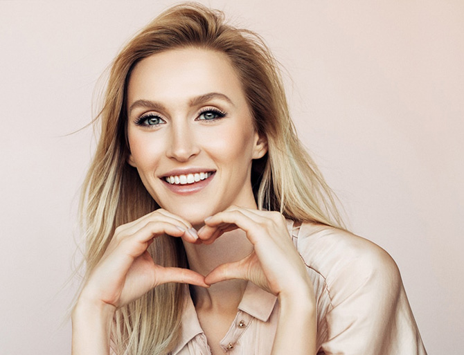 Stock image of a smiling girl posing love symbol with her hands