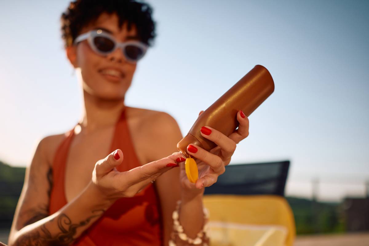 Close up of woman applying sunscreen outdoors.